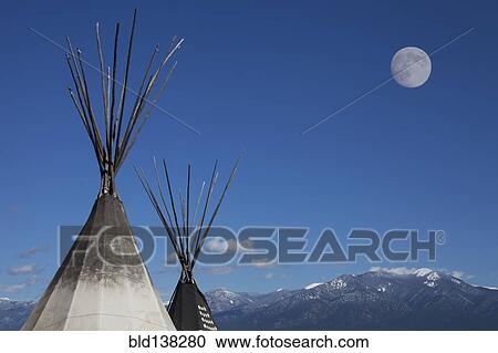 Stock Image - Teepees under full moon in blue sky. Fotosearch