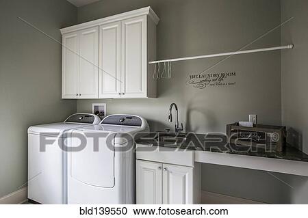 Stock Image - Washing machine, dryer and sink in laundry room. Fotosearch