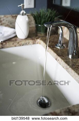 Water flowing from faucet in modern bathroom sink View Large Photo Image Stock Photo - Water flowing from faucet in modern bathroom sink. Fotosearch