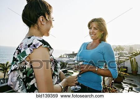Stock Photo - Women drinking wine at waterfront. Fotosearch