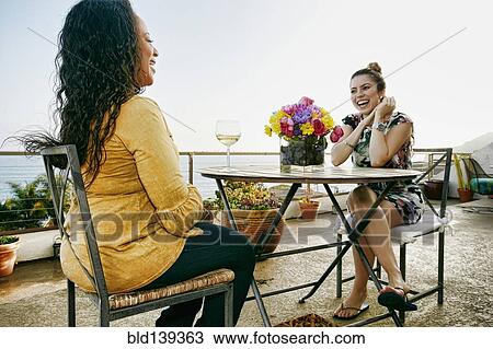 Stock Image - Women drinking wine together at waterfront. Fotosearch