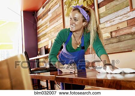 Stock Photo - Caucasian server wiping down tables in cafe. Fotosearch