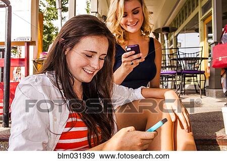 Caucasian teenage girls using cell phones in city View Large Photo Image Stock Photo - Caucasian teenage girls using cell phones in city. Fotosearch
