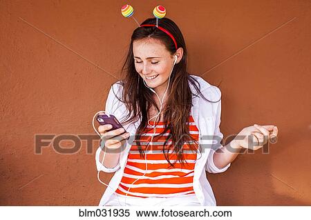 Stock Photography - Caucasian woman in novelty antenna listening to mp3 player. Fotosearch