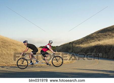 Stock Photo - Couple riding opposing tandem bicycle on rural road. Fotosearch