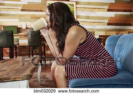 Stock Photo - Hispanic woman drinking coffee in cafe. Fotosearch