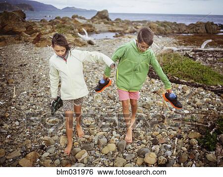 Mixed race brother and sister carrying their shoes on rocky beach View Large Photo Image Stock Photograph - Mixed race brother and sister carrying their shoes on rocky beach. Fotosearch