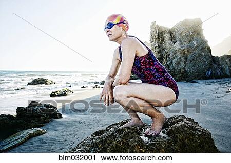 Older Caucasian woman crouching on rock on beach View Large Photo Image Stock Image - Older Caucasian woman crouching on rock on beach. Fotosearch