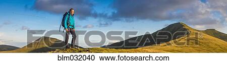 Panoramic view of hiker walking up grassy hill View Large Photo Image Stock Image - Panoramic view of hiker walking up grassy hill. Fotosearch