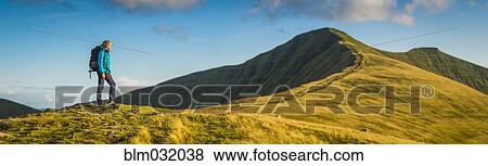 Panoramic view of hiker walking up grassy hill View Large Photo Image Stock Photo - Panoramic view of hiker walking up grassy hill. Fotosearch