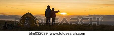 Stock Photo - Silhouette of hikers overlooking remote landscape at sunset. Fotosearch