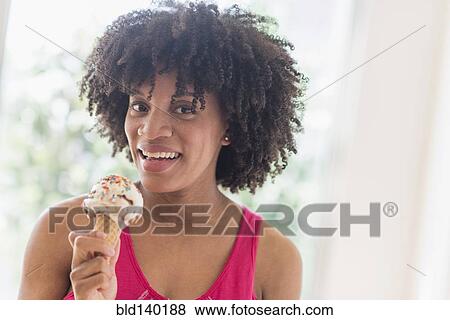 Stock Photo - African American woman eating ice cream cone. Fotosearch