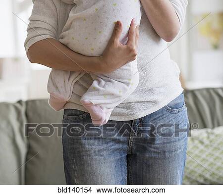 Asian mother holding baby in living room View Large Photo Image Picture - Asian mother holding baby in living room. Fotosearch