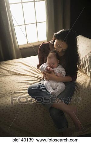 Asian mother holding baby on bed View Large Photo Image Stock Photo - Asian mother holding baby on bed. Fotosearch
