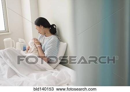 Stock Image - Asian mother holding newborn baby in hospital. Fotosearch