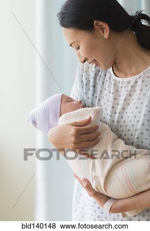 Asian mother holding newborn baby in hospital View Large Photo Image Stock Photo - Asian mother holding newborn baby in hospital. Fotosearch