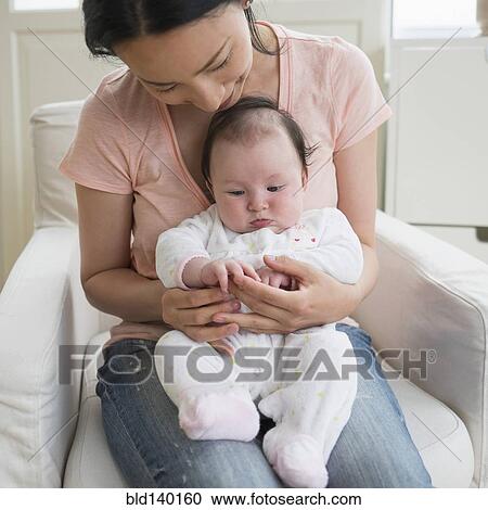 Stock Image - Asian mother playing with baby in living room. Fotosearch
