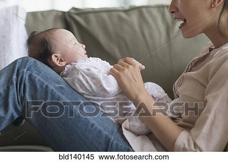 Stock Photography - Asian mother playing with baby in living room. Fotosearch