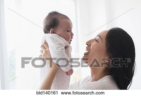 Stock Image - Asian mother playing with baby. Fotosearch