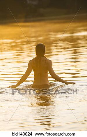 Picture - Asian woman standing in lake. Fotosearch
