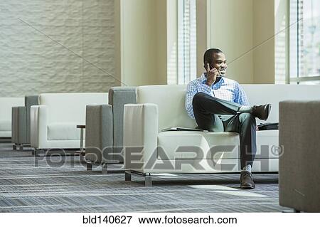 Black businessman talking on cell phone in office lobby View Large Photo Image Stock Photo - Black businessman talking on cell phone in office lobby. Fotosearch