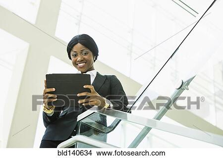 Black businesswoman using digital tablet on office staircase View Large Photo Image Picture - Black businesswoman using digital tablet on office staircase. Fotosearch