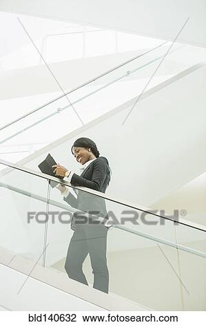Black businesswoman using digital tablet on office staircase View Large Photo Image Stock Image - Black businesswoman using digital tablet on office staircase. Fotosearch