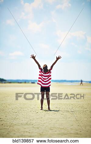 Black girl standing with arms raised on beach View Large Photo Image Stock Photo - Black girl standing with arms raised on beach. Fotosearch