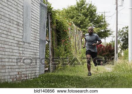 Black man running in urban grass View Large Photo Image Stock Photograph - Black man running in urban grass. Fotosearch