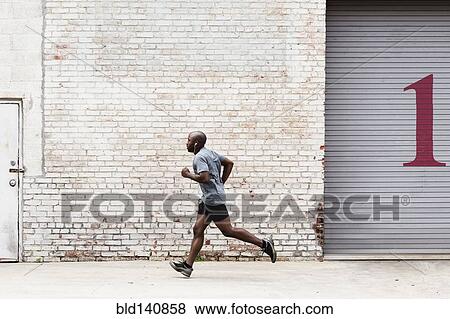 Stock Photo - Black man running on city sidewalk. Fotosearch