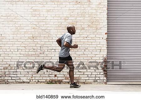Black man running on city sidewalk View Large Photo Image Stock Photo - Black man running on city sidewalk. Fotosearch