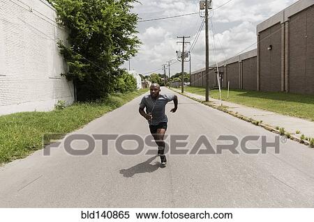 Black man running on city street View Large Photo Image Stock Photography - Black man running on city street. Fotosearch