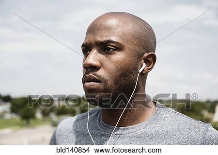 Picture - Black runner listening to earbuds. Fotosearch
