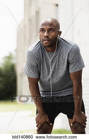 Black runner resting in city with earbuds View Large Photo Image Stock Image - Black runner resting in city with earbuds. Fotosearch