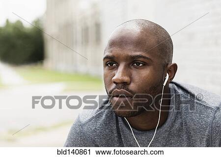 Black runner resting in city with earbuds View Large Photo Image Stock Image - Black runner resting in city with earbuds. Fotosearch