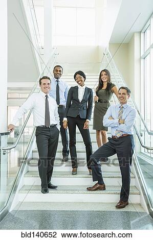Stock Image - Business people smiling on office staircase. Fotosearch