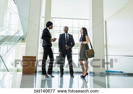 Stock Photo - Business people talking in office hallway. Fotosearch