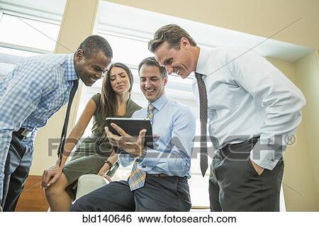 Business people using digital tablet in office View Large Photo Image Stock Photograph - Business people using digital tablet in office. Fotosearch