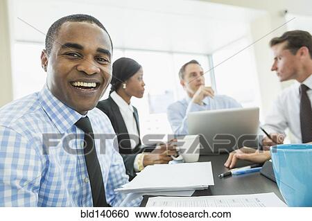 Businessman smiling in meeting View Large Photo Image Stock Image - Businessman smiling in meeting. Fotosearch