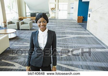 Stock Photo - Businesswoman smiling in office lobby. Fotosearch
