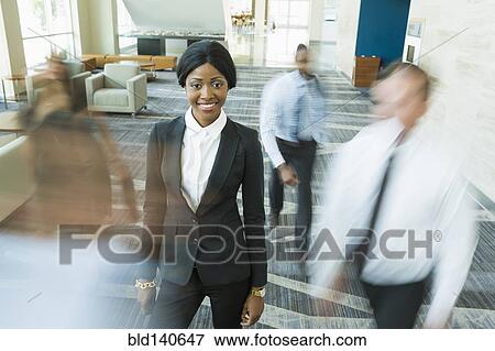 Businesswoman standing still in busy office lobby View Large Photo Image Stock Photo - Businesswoman standing still in busy office lobby. Fotosearch