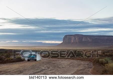 Stock Image - Car driving on dirt road in desert, Monument Valley, Utah, United States. Fotosearch