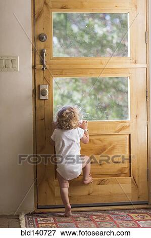 Caucasian baby boy peering out door window View Large Photo Image Stock Photo - Caucasian baby boy peering out door window. Fotosearch