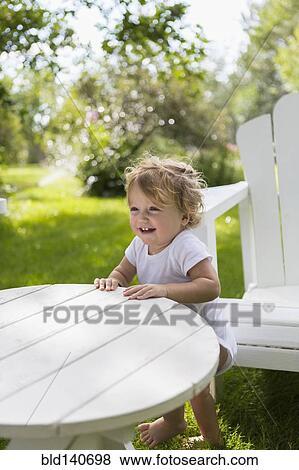 Caucasian baby boy standing at table in backyard View Large Photo Image Stock Photo - Caucasian baby boy standing at table in backyard. Fotosearch