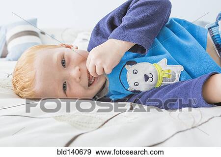 Stock Photo - Caucasian boy smiling on bed. Fotosearch