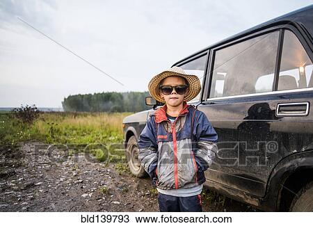 Caucasian boy standing near car in rural field View Large Photo Image Stock Image - Caucasian boy standing near car in rural field. Fotosearch