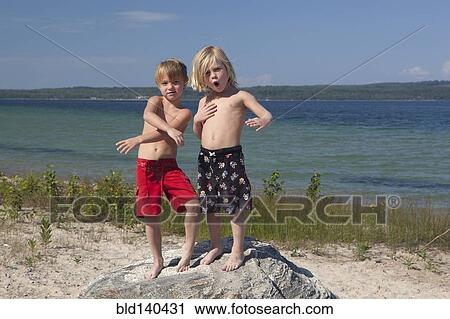 Caucasian boys standing on rock at beach View Large Photo Image Stock Image - Caucasian boys standing on rock at beach. Fotosearch