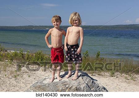 Caucasian boys standing on rock on beach View Large Photo Image Stock Image - Caucasian boys standing on rock on beach. Fotosearch