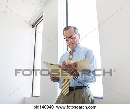Caucasian businessman reading folder in office View Large Photo Image Stock Image - Caucasian businessman reading folder in office. Fotosearch