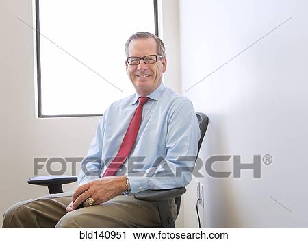 Stock Image - Caucasian businessman smiling in office. Fotosearch